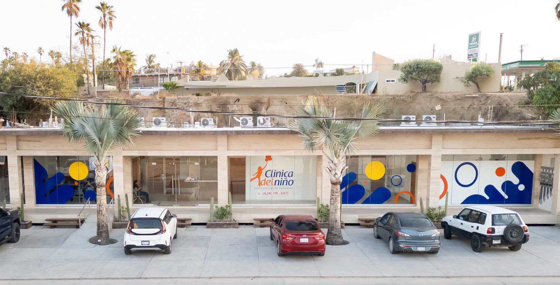 Fachada de Clínica del Niño, consultorio de especialistas en pediatría en Los Cabos, con estacionamiento y palmeras al frente